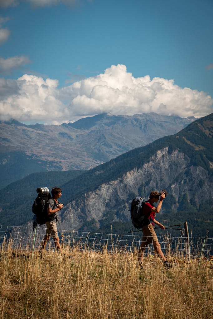 Two men hiking in stunning mountainous terrain under a bright blue sky.